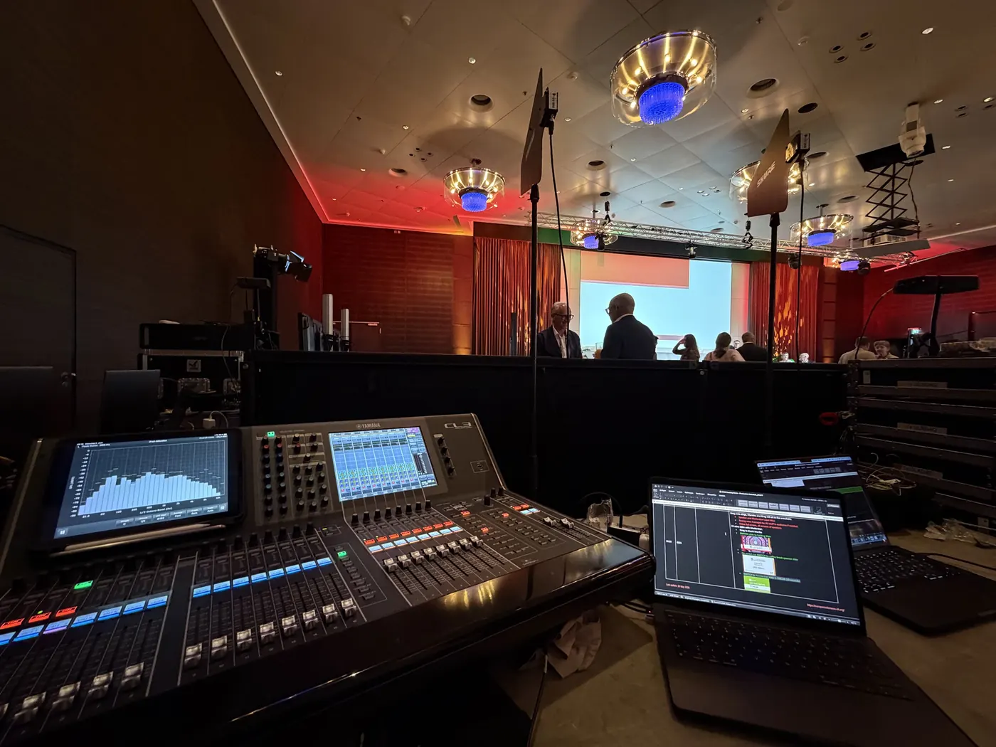 Digitalmischpult mit Laptop am Technikplatz in einem Saal mit rotem Licht