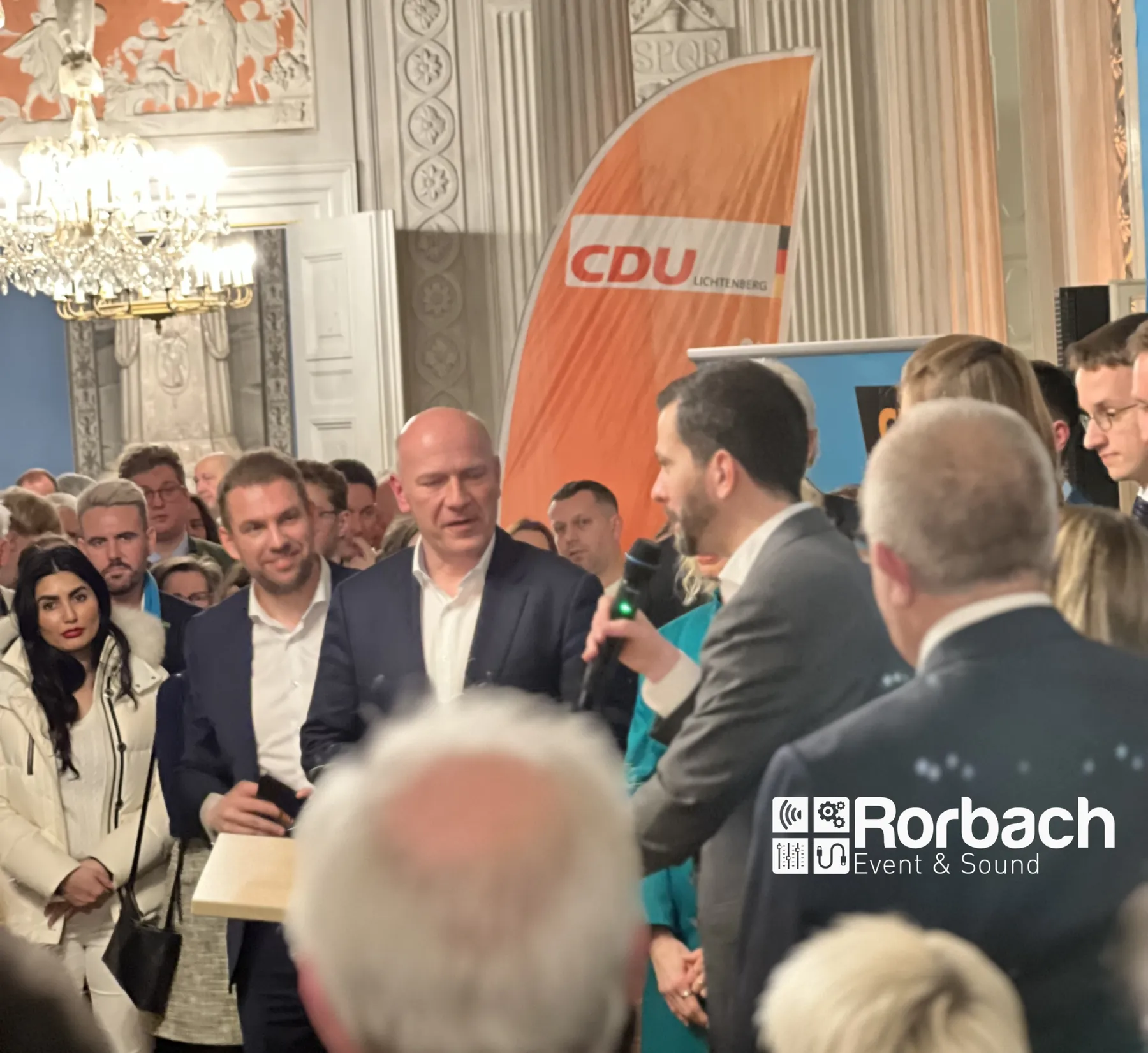 Gäste und Redner mit Mikrofon bei einem Empfang in einem Festsaal