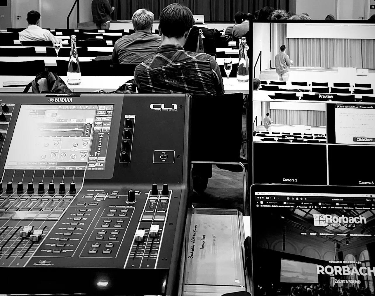 Yamaha-Mischpult und Monitore mit Kamerabildern am Regieplatz einer Konferenz, schwarz-weiß