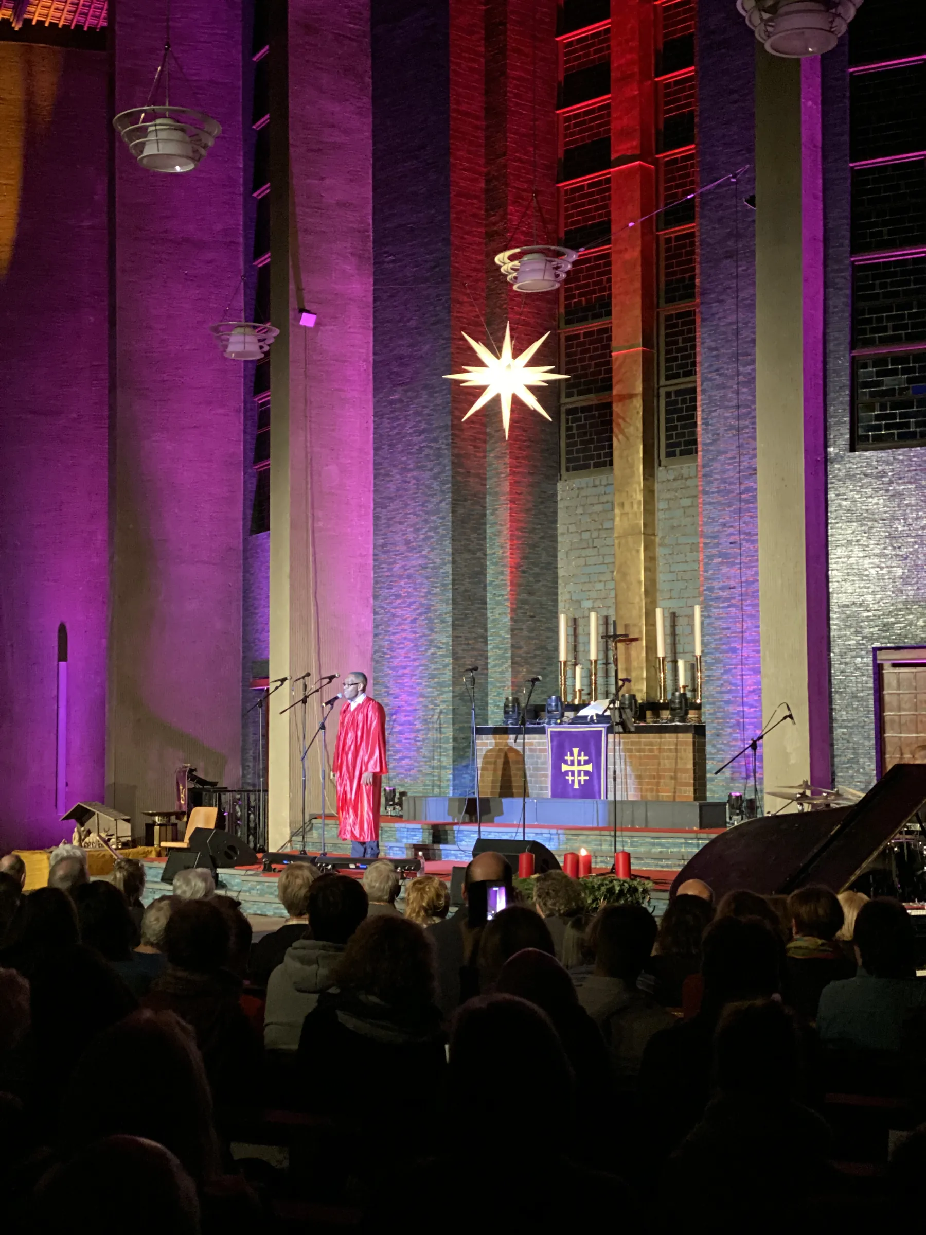 Kirchenraum in violettem und rotem Licht mit Leuchtstern über dem Altar